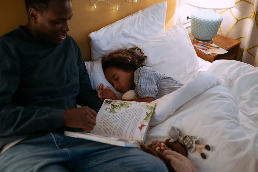 A father reading a bedtime story to his child, something you can do when Adapting Children's Familiar Sleep Routines to Your New Home.
