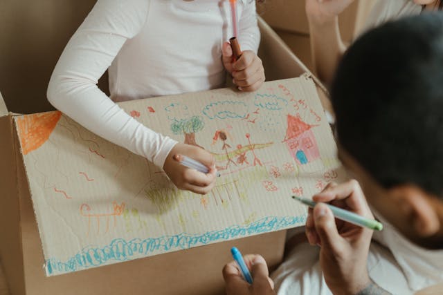 Kid drawing on a moving box while packing