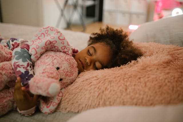 Little girl sleeping and hugging her comfort toy as an example of strategies for sleep coaching during a move