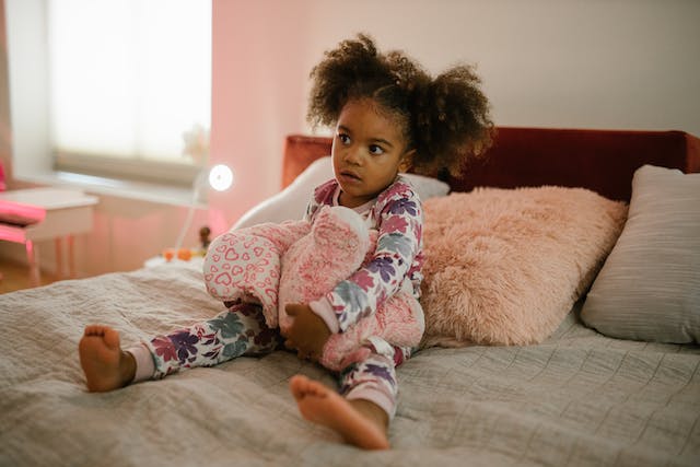 Little girl in pajamas sitting on bed