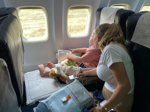 Woman playing with her daughter on the plane after exploring minimizing jet lag in children